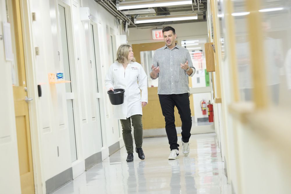 Two lab members talking as they walk down the lab corridor